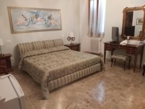um quarto com uma cama, uma mesa e um espelho em Antica casa di famiglia em Castiglione del Lago