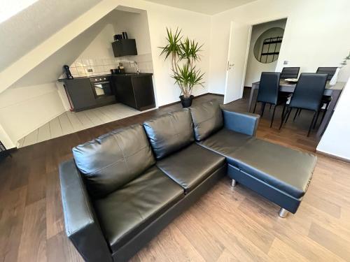 a black leather couch in a living room with a table at Ferienwohnung Augenblick - Stylisches Apartment in der besten Altstadtlage von Erfurt in Erfurt