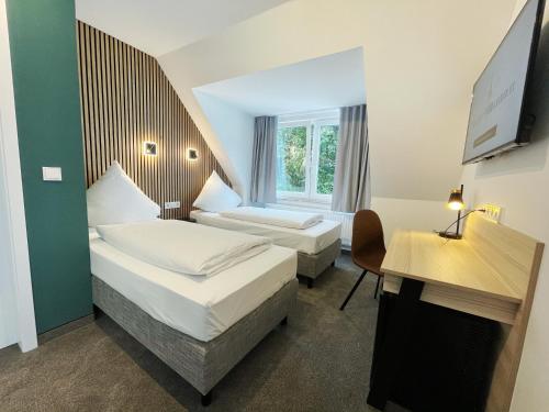 a hotel room with two beds and a desk at Hotel Xenia Flensburg in Flensburg