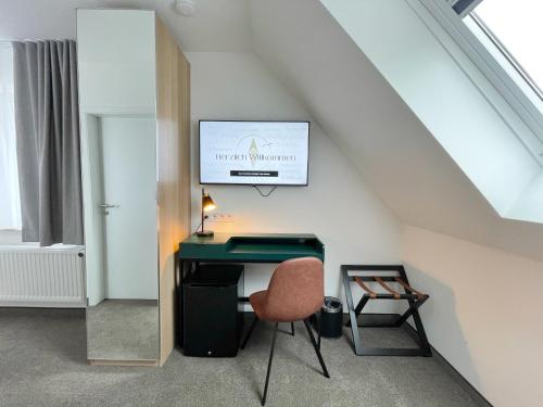 Zimmer mit einem Schreibtisch, einem Stuhl und einem TV in der Unterkunft Hotel Xenia Flensburg in Flensburg
