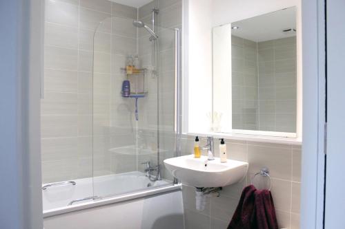 uma casa de banho com um lavatório, uma banheira e um espelho. em Bridgewater House - Private Room & Bathroom Near Etihad and CoOp Arena em Manchester
