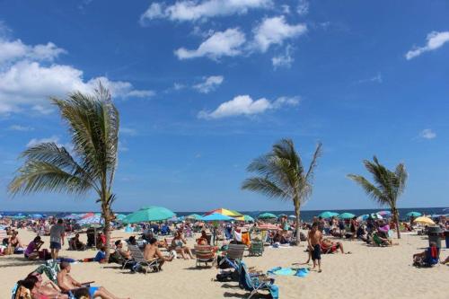 a crowd of people on a beach with palm trees at Spacious beach home ready for Family Memories! in Point Pleasant Beach