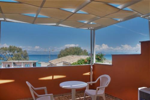 a patio with a table and chairs and a view of the ocean at Hotel Benitses Arches in Benitses