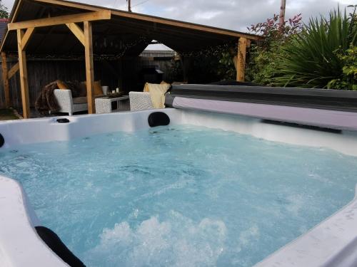 a hot tub with blue water in a backyard at Pheasants Retreat with Hot Tub and Fire Pit in Trefnant