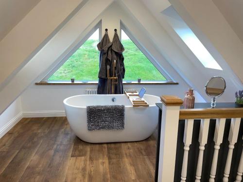 a bathroom with a large white bath tub in front of a window at Beechwood Nook- Crown Lodges in Crawshaw Booth