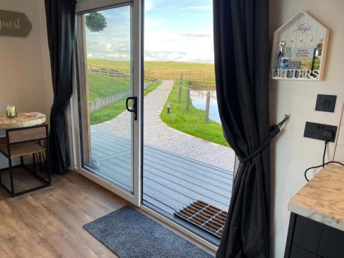 a sliding glass door with a view of a field at Beechwood Nook- Crown Lodges in Crawshaw Booth