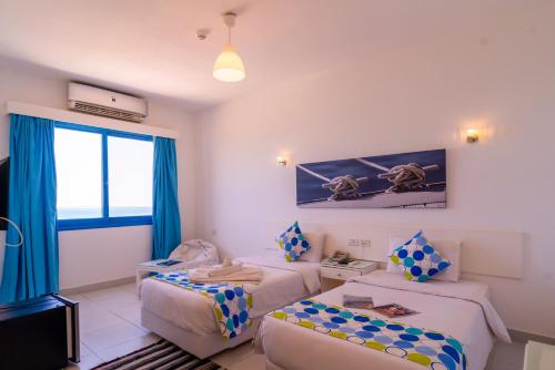 a hotel room with two beds and a window at Lagoonie Lodge & Beach in Hurghada