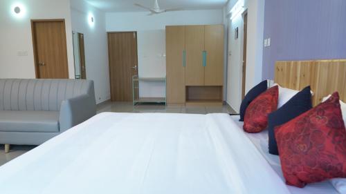 a bedroom with a large white bed and a couch at The White Orchid Luxury Service Apartments in Ernakulam