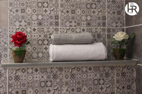 ein Badezimmer mit einem Regal mit Handtüchern und Blumen in der Unterkunft Hotel al rayan in Tataouine