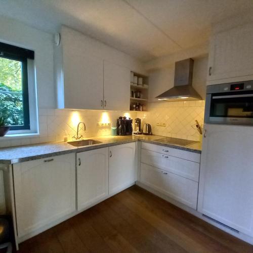 a kitchen with white cabinets and a sink at Vakantiehuis met sauna en jacuzzie in Lunteren