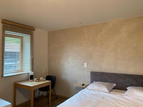 a bedroom with a bed and a desk and a table at B&B elzartwinning in Hasselt