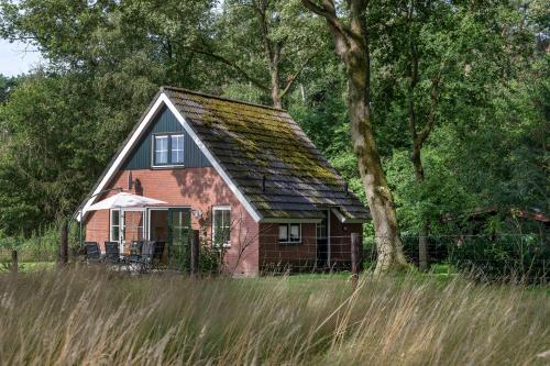 a red barn with a black roof in a field at Natuurhuisje ‘t Oetzicht in Markelo