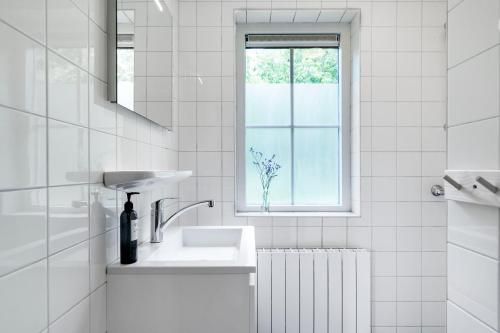 a white bathroom with a sink and a window at Natuurhuisje ‘t Oetzicht in Markelo