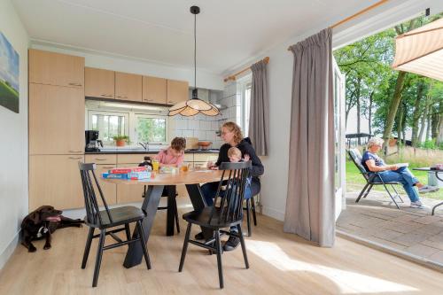 a woman and two children sitting at a table in a kitchen at Natuurhuisje ‘t Oetzicht in Markelo