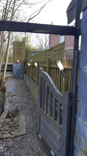 a wooden fence next to a blue building at LA P'TITE MAISON in Charleroi