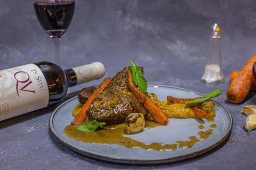 a plate of meat and vegetables with a bottle of wine at Termas El Corazon in San Esteban