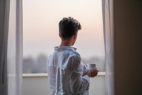 a man is holding a coffee cup looking out of a window at The President Hotel Cairo in Cairo
