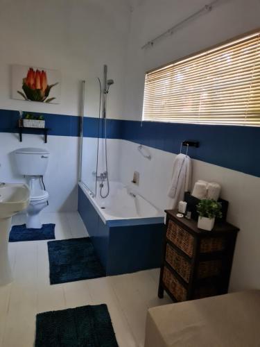 ein Badezimmer mit einer Badewanne, einem WC und einem Waschbecken in der Unterkunft The Garden Inn Guesthouse in Modimolle