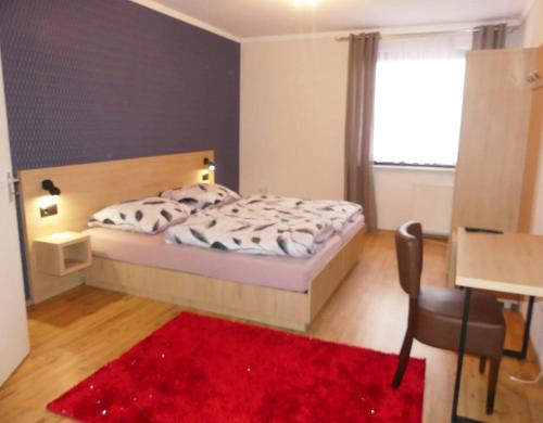Schlafzimmer mit einem Bett und einem roten Teppich in der Unterkunft Hotel Akropolis in Herford