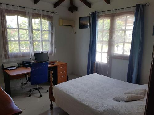 um quarto com uma cama e uma secretária com um computador em Villa Thomas bouillante em Bouillante