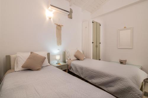 two beds in a room with white walls at Villa Daniela - Private Pool and Serene Location, by ZanteWize in Koríthion