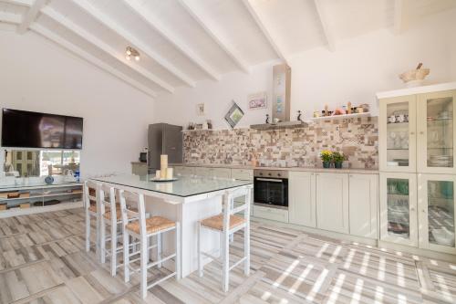 a kitchen with white cabinets and a island with stools at Villa Daniela - Private Pool and Serene Location, by ZanteWize in Koríthion