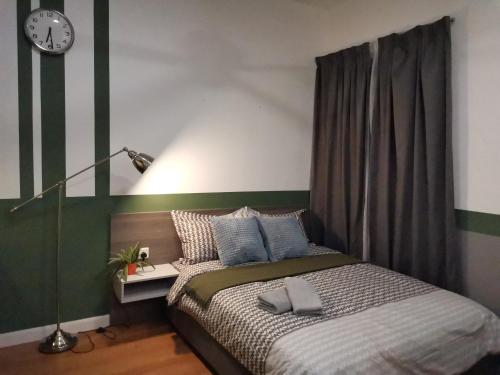 a bedroom with a bed and a clock on the wall at HIJAU Geniehome 2BR1studio Free 99mbps WIFI and Carpark at Utropolis Shah Alam in Shah Alam