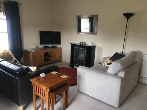 a living room with two couches and a fireplace at Peel House Apartments in Burton upon Trent