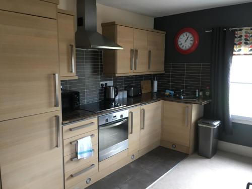 una cocina con armarios de madera y un reloj en la pared en Peel House Apartments, en Burton upon Trent