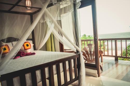 1 dormitorio con cama con dosel y balcón en Flora and Fauna Mirissa en Mirissa
