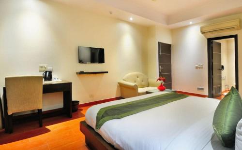 Dormitorio con cama, escritorio y TV en Zenith Mahipalpur - Free Parking, en Nueva Delhi