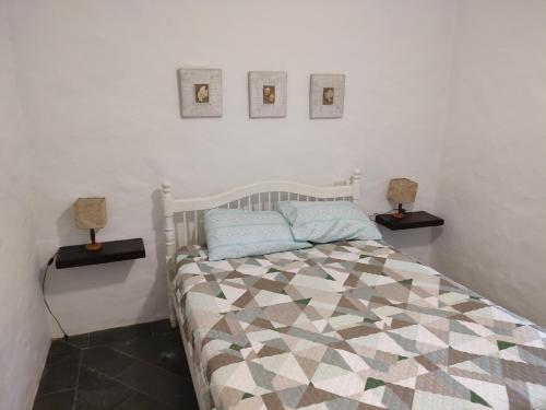 Un dormitorio con una cama con tres cuadros en la pared. en Casa aconchegante em Guaeca - 8 pessoas, en São Sebastião