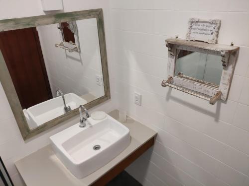 a white bathroom with a sink and a mirror at Casa aconchegante em Guaeca - 8 pessoas in São Sebastião