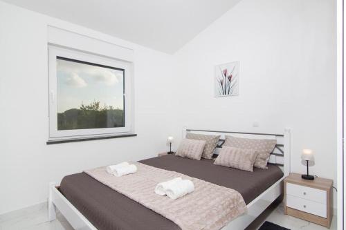 biała sypialnia z dużym łóżkiem i oknem w obiekcie Apartments Talić Fažana w Fažanie