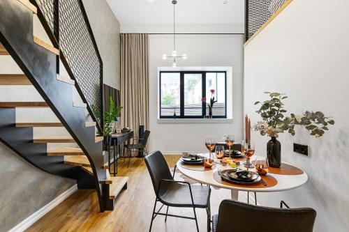 una sala da pranzo con tavolo, sedie e scala di Bob W Duo Lofts a Tartu