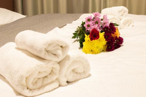 a pile of towels and a bouquet of flowers on a bed at Odmorište Luna in Olovo