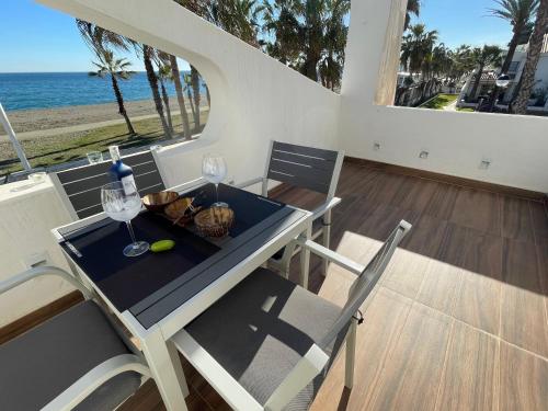 a table and chairs with wine glasses and the ocean at Casa Haisea 2 in Caleta De Velez