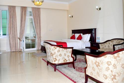 a bedroom with a bed and two chairs at Panorama Portico Hotel, Juba in Juba