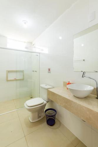 a white bathroom with a toilet and a sink at Espaço Barão - Área de Lazer in Araraquara