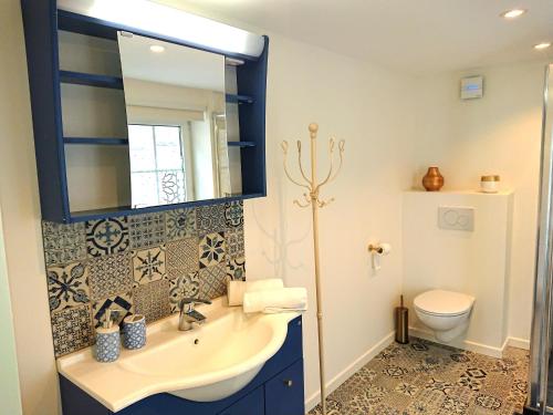 een badkamer met een wastafel, een spiegel en een toilet bij 1001 Nuits in Aywaille