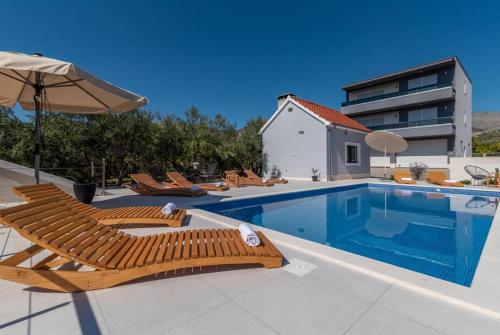 - une piscine avec des chaises longues et un parasol dans l'établissement Villa Dalmata, à Trogir