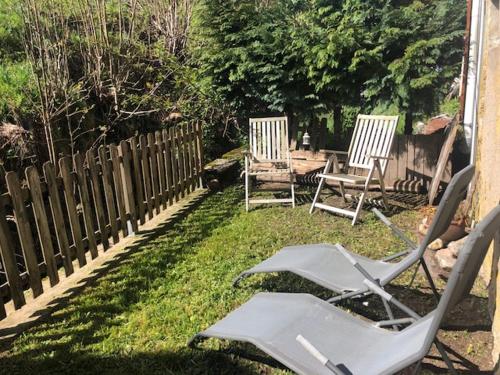 dos sillas de jardín sentadas en el césped junto a una valla en Le Valtinet, séjour esprit montagne, en Le Valtin