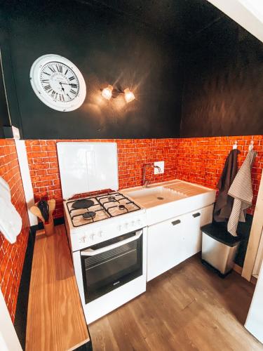 a kitchen with a stove and a clock on the wall at Grand Studio « Ô Soleil » 4 pers. 200m des pistes. in La Salle Les Alpes