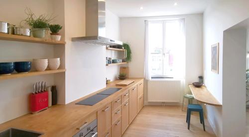 a kitchen with wooden cabinets and a table and a window at Appartement et parking privatif le long de l Escaut in Tournai