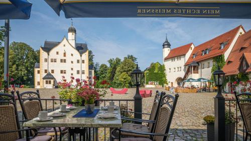 a table and chairs in a courtyard with buildings at Schlosshotel Klaffenbach in Chemnitz