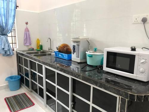 eine Küchentheke mit Mikrowelle und Spüle in der Unterkunft Tok Chik Homestay in Kampong Lubok Bedil