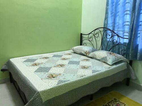 een bed met een dekbed en kussens in een slaapkamer bij Tok Chik Homestay in Kampong Lubok Bedil