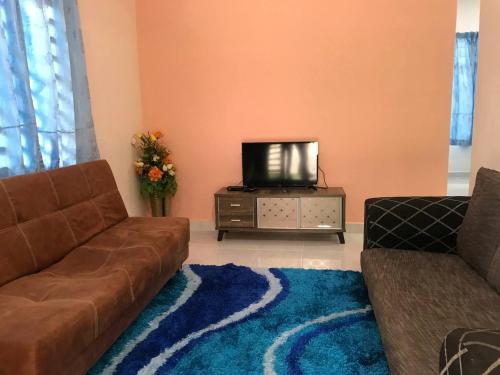 ein Wohnzimmer mit einem Sofa und einem TV in der Unterkunft Tok Chik Homestay in Kampong Lubok Bedil