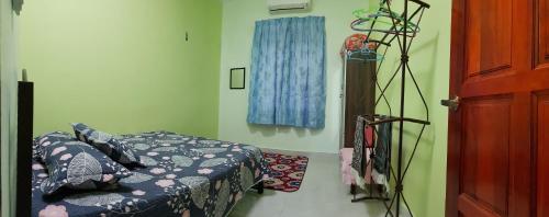 een slaapkamer met een bed en een blauwe deken bij Tok Chik Homestay in Kampong Lubok Bedil