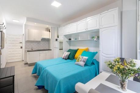 Cet appartement comprend une chambre avec un lit bleu et une cuisine. dans l'établissement Estudio W&G Las Canteras con bonitas vistas al mar, à Las Palmas de Gran Canaria